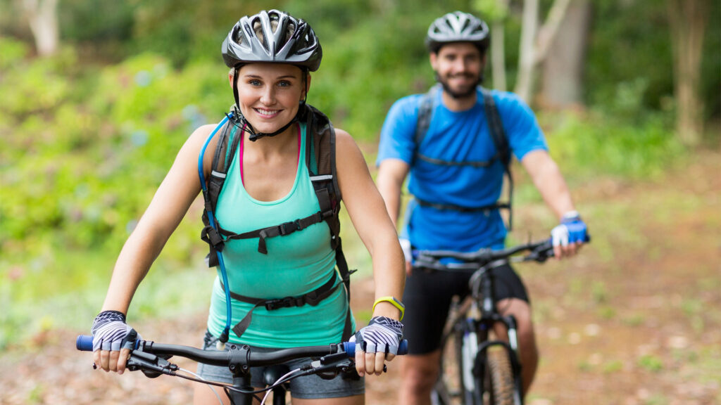 Smiling athletic couple cycling in forest