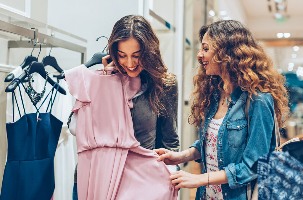 Two young women choosing dresses in a luxury fashion store