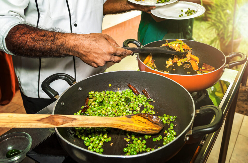 Chef at a cooking demonstration of Indian Ayurvedic cuisine gives samples of dishes from pans to plates