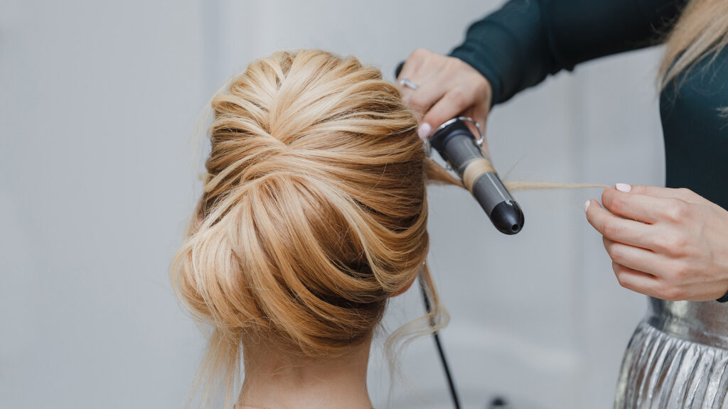 closeup of professional hairdresser hands doing beauty hairstyle a-la french twist