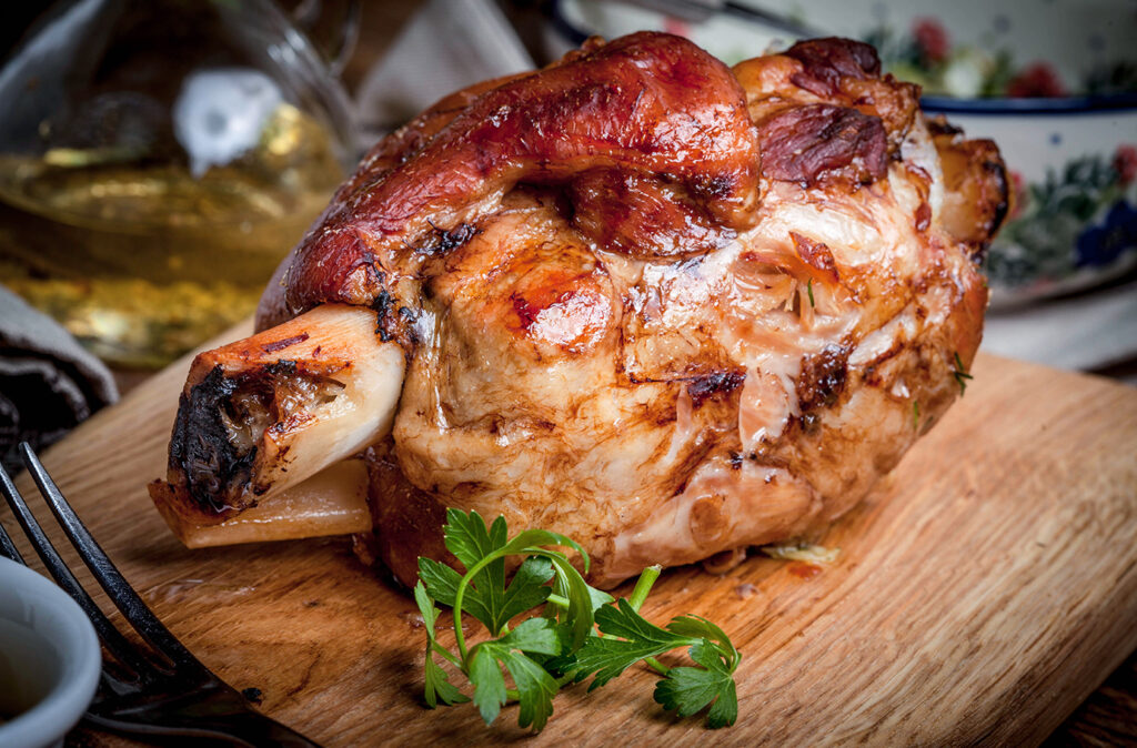 Roast pork knuckle on a wooden board. Selective focus.