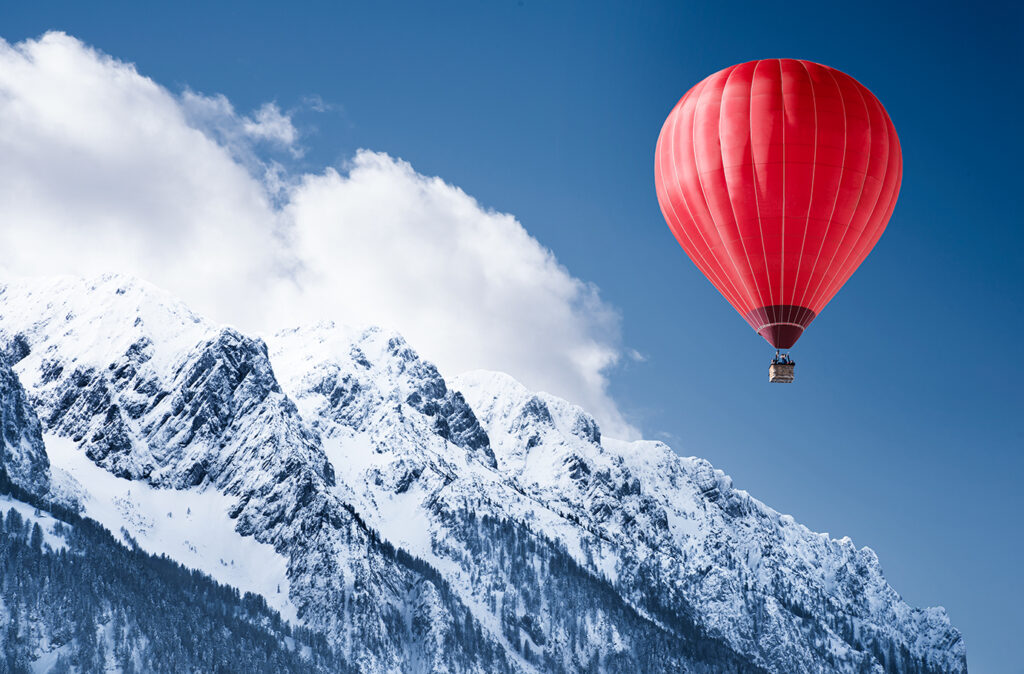 Colorful hot-air balloon flying over snowcapped mountain