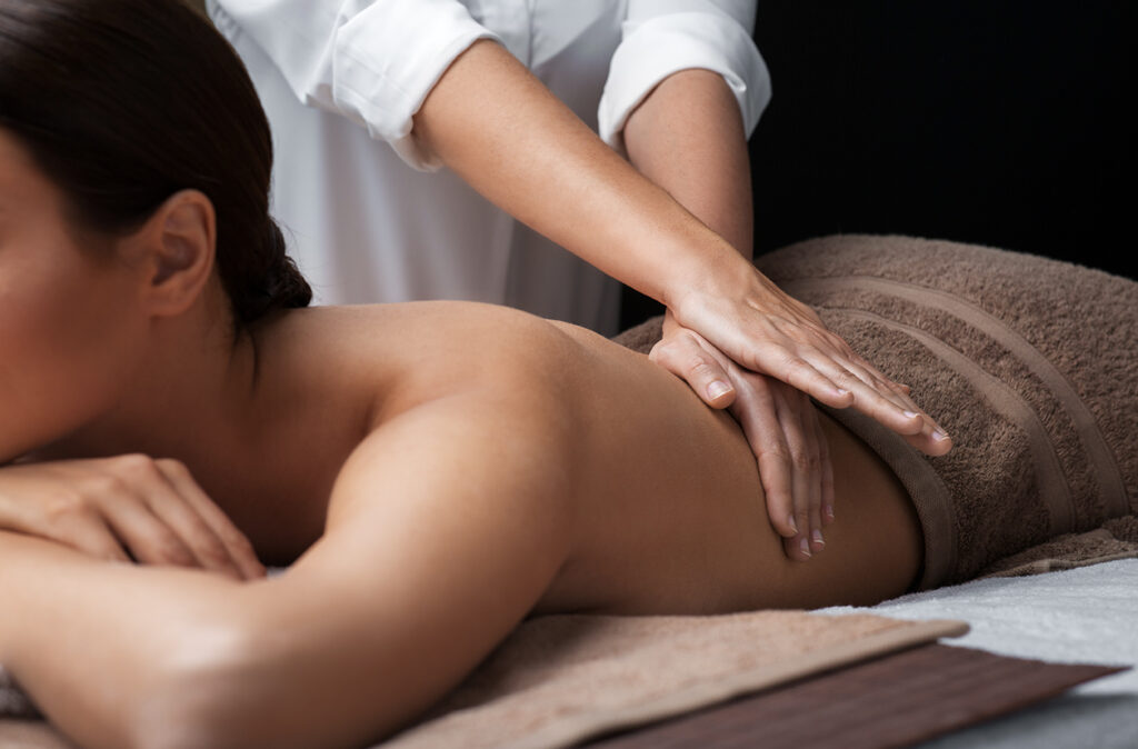 wellness, beauty and relaxation concept - beautiful young woman lying and having back massage at spa