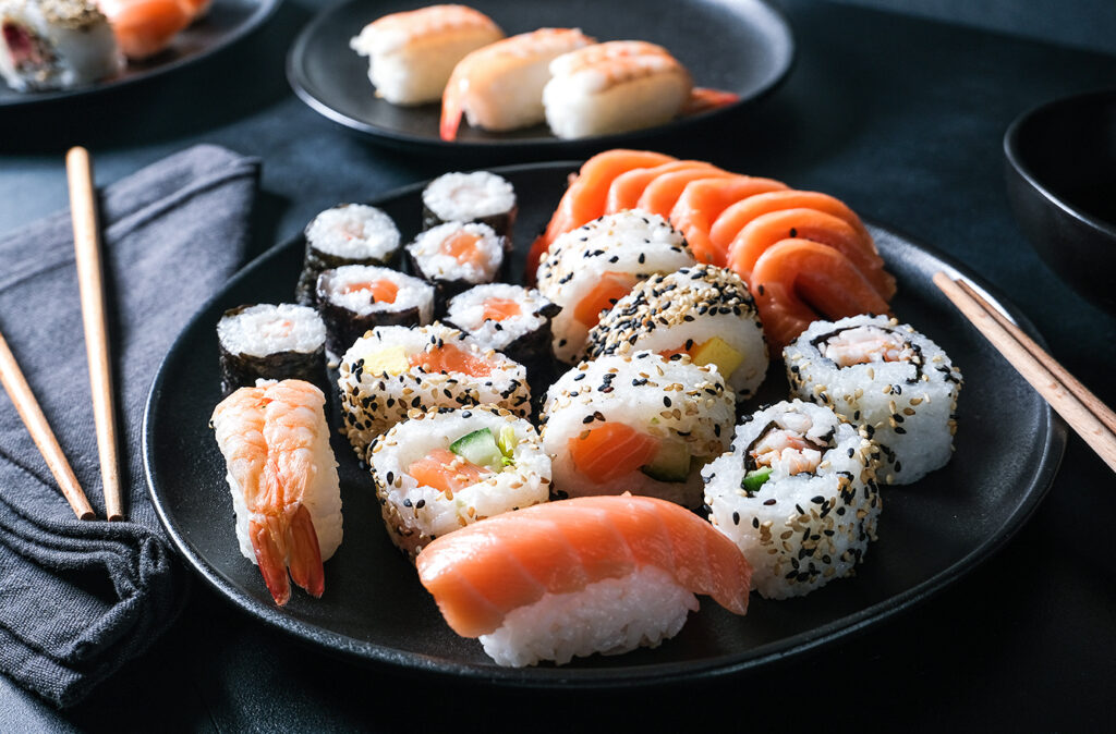 Lunch at the sushi bar. Set of sushi and rolls unagi maki on a black plate on dark background top view. Sushi Delivery to Home Order Online. Takeout coronavirus food.