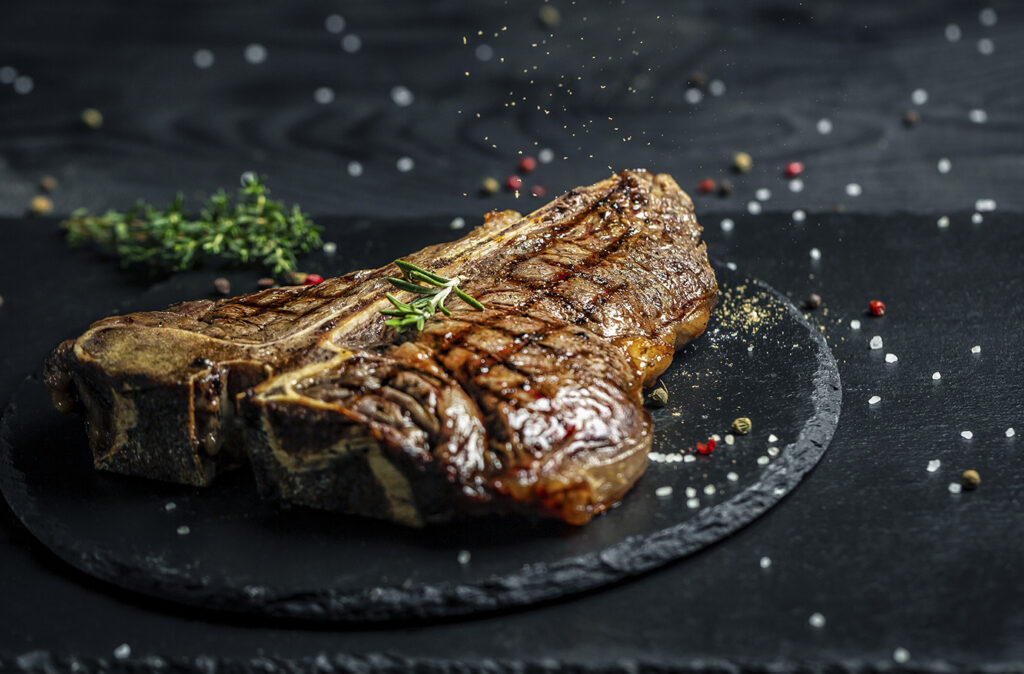 T-bone grilled beef steak. Dry Aged Barbecue Porterhouse Steak. Medium rare. American cuisine. Long banner format, top view.