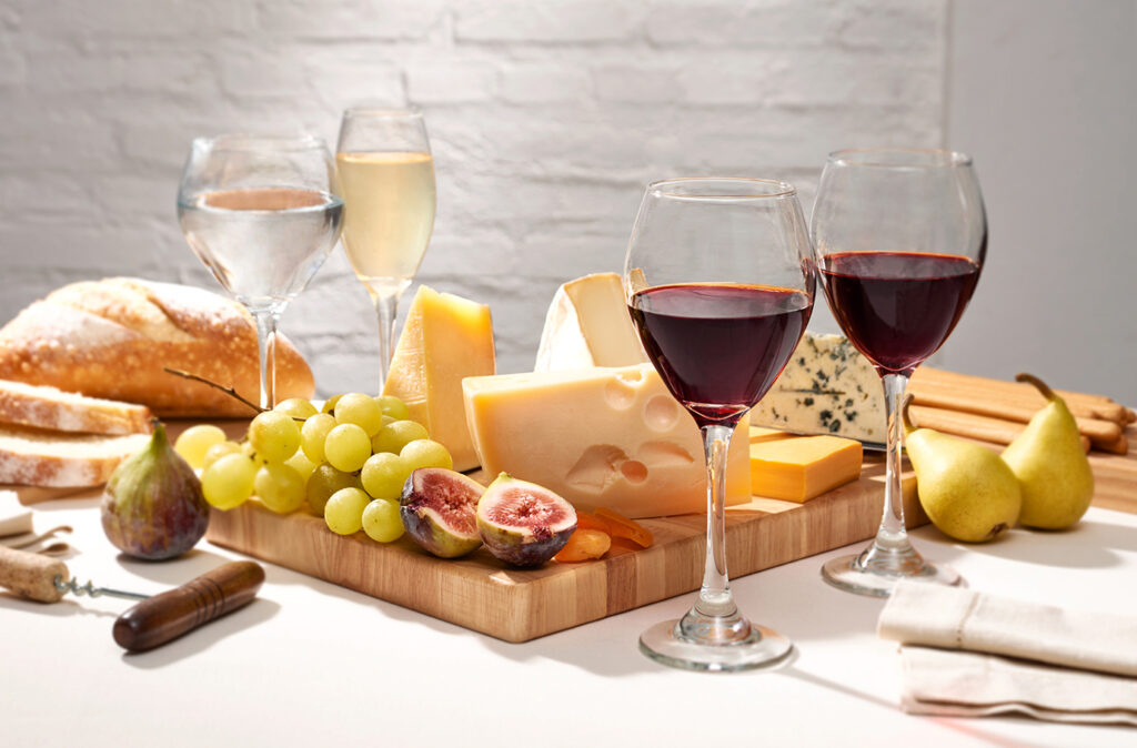 Table with cheese and fruit board, accompanied by different wines