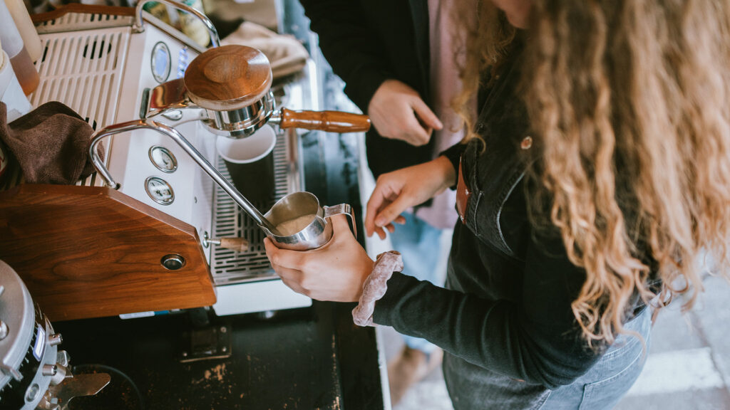 Training time for new workers at a coffee shop, coworkers helping in the learning process.  Shot in Seattle, Washington, USA.