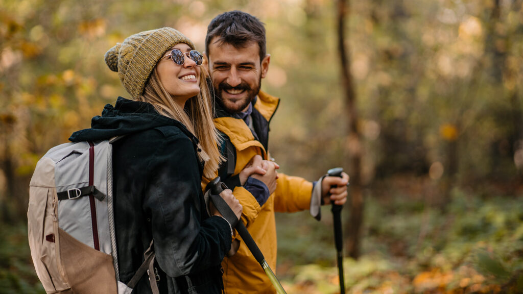 Young couple hiking. Hugging and smiling while walking and having a good time together