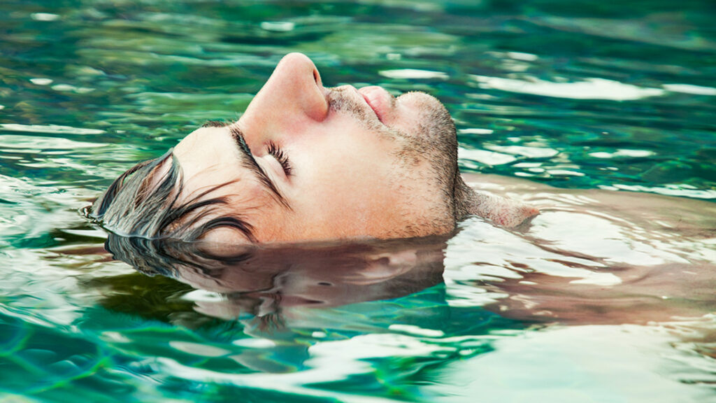 Portrait of a young man relaxing in the swimming pool