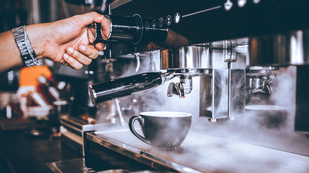 Barista making fresh coffee with machine in coffee shop or cafe.