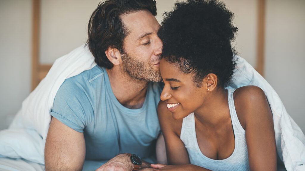 Shot of an affectionate middle aged man kissing his wife on her forehead while relaxing on their bed at home