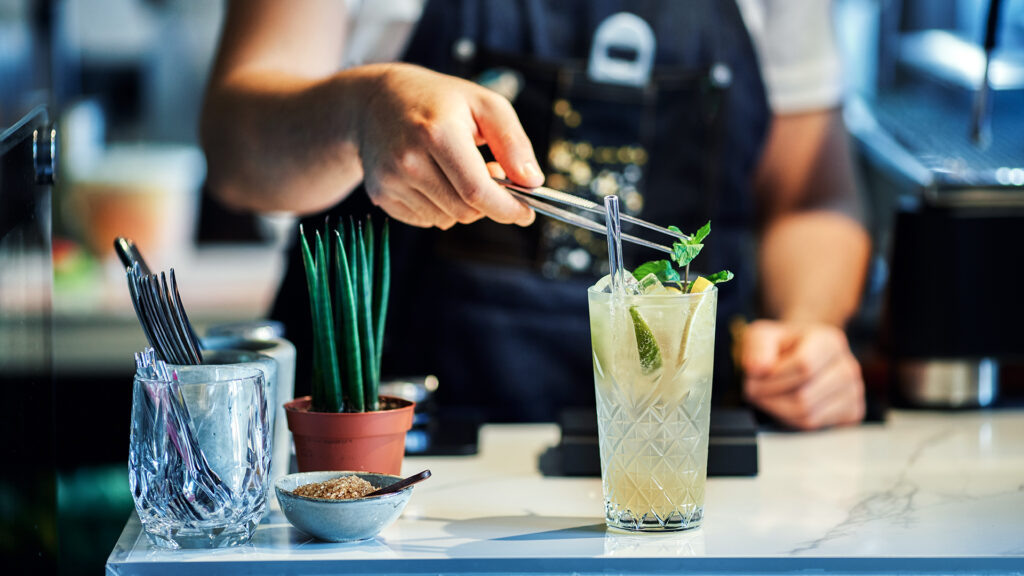 Close up of bartender mixing cocktail garnished with fresh mint leaves