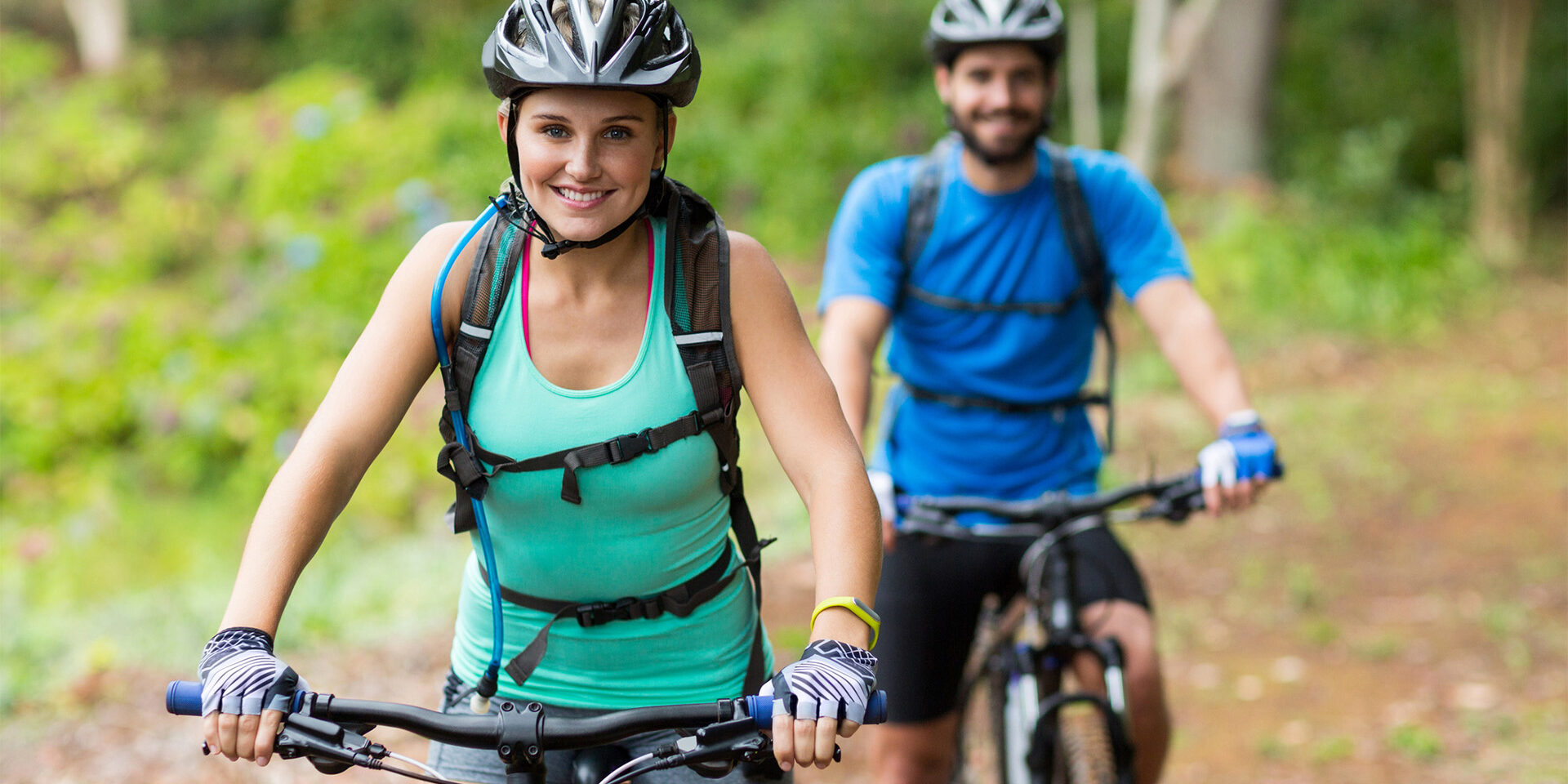 Smiling athletic couple cycling in forest Smiling athletic couple cycling in forest