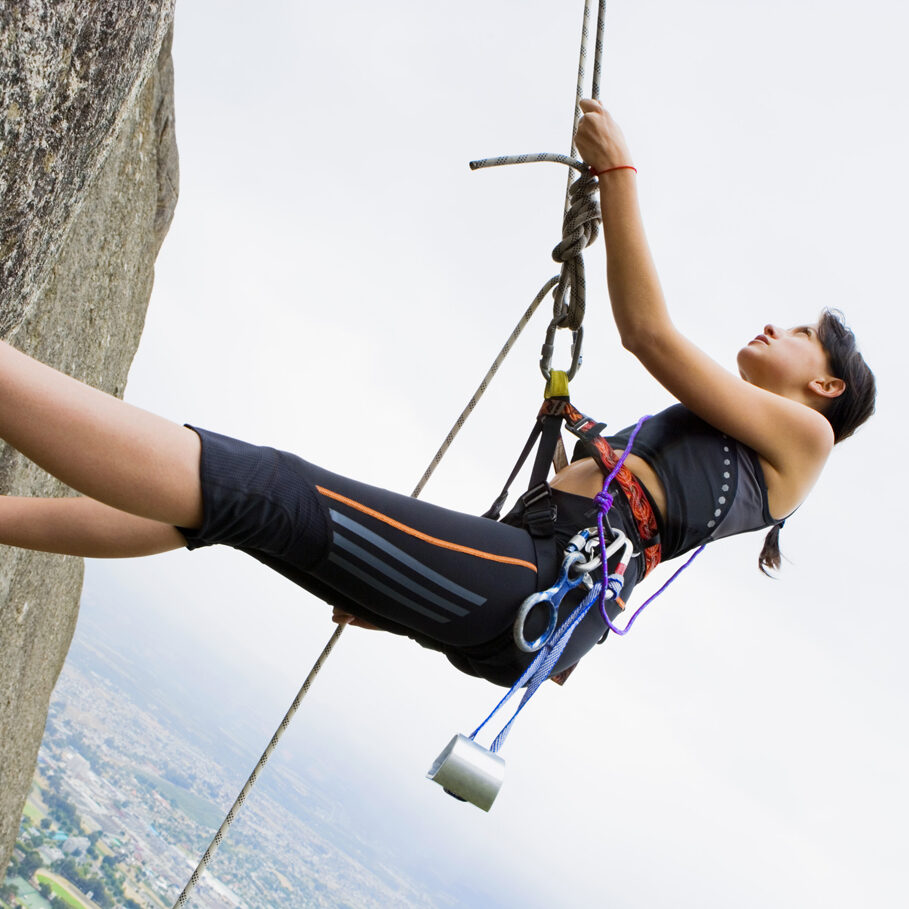 Couple rock climbing on steep cliff