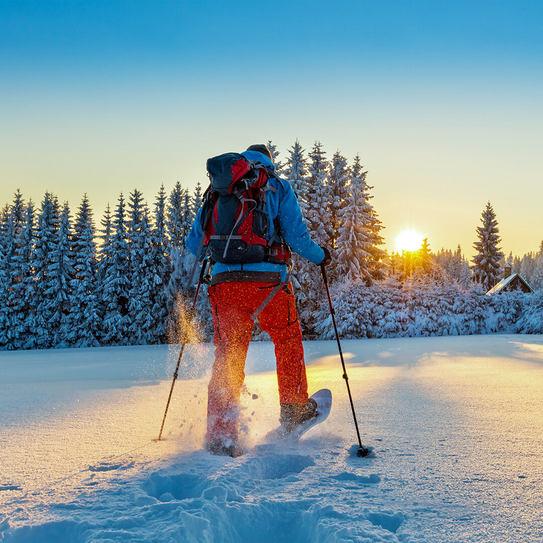 Snowshoe walker running in powder snow with beautiful sunrise light. Outdoor winter activity and healthy lifestyle