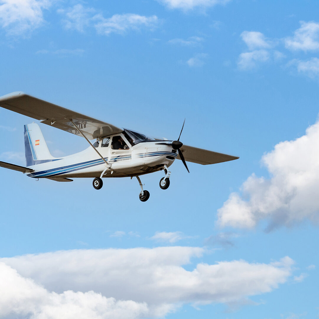 Single engine ultralight plane flying in the blue sky with white clouds