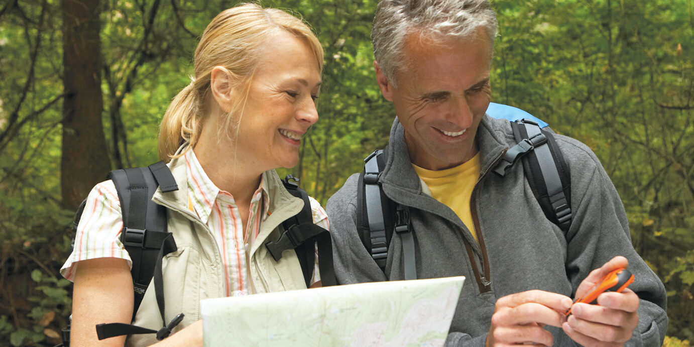 GPS Schatzsuche Mature man and woman looking at map and using GPS in forest