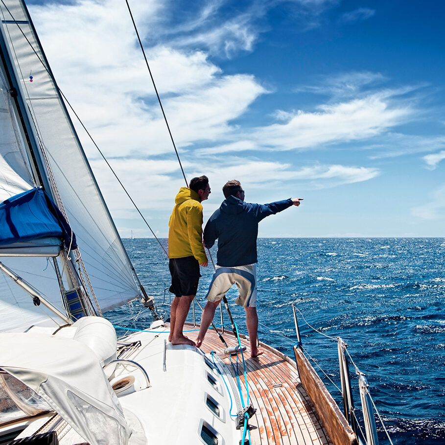 Sailing crew members on sailing ship observing the sea.