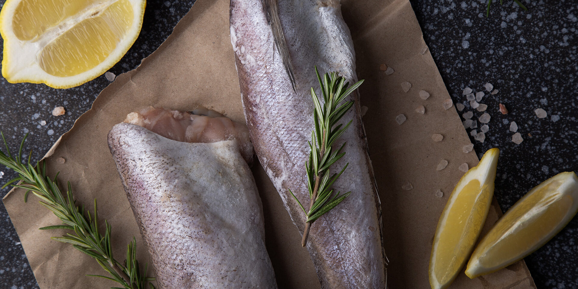 fish hake seasoned with herbs, pepper and lemon on a rustic wooden board, for recipes or seafood market displays. fish hake seasoned with herbs, pepper and lemon on a rustic wooden board, for recipes or seafood market displays