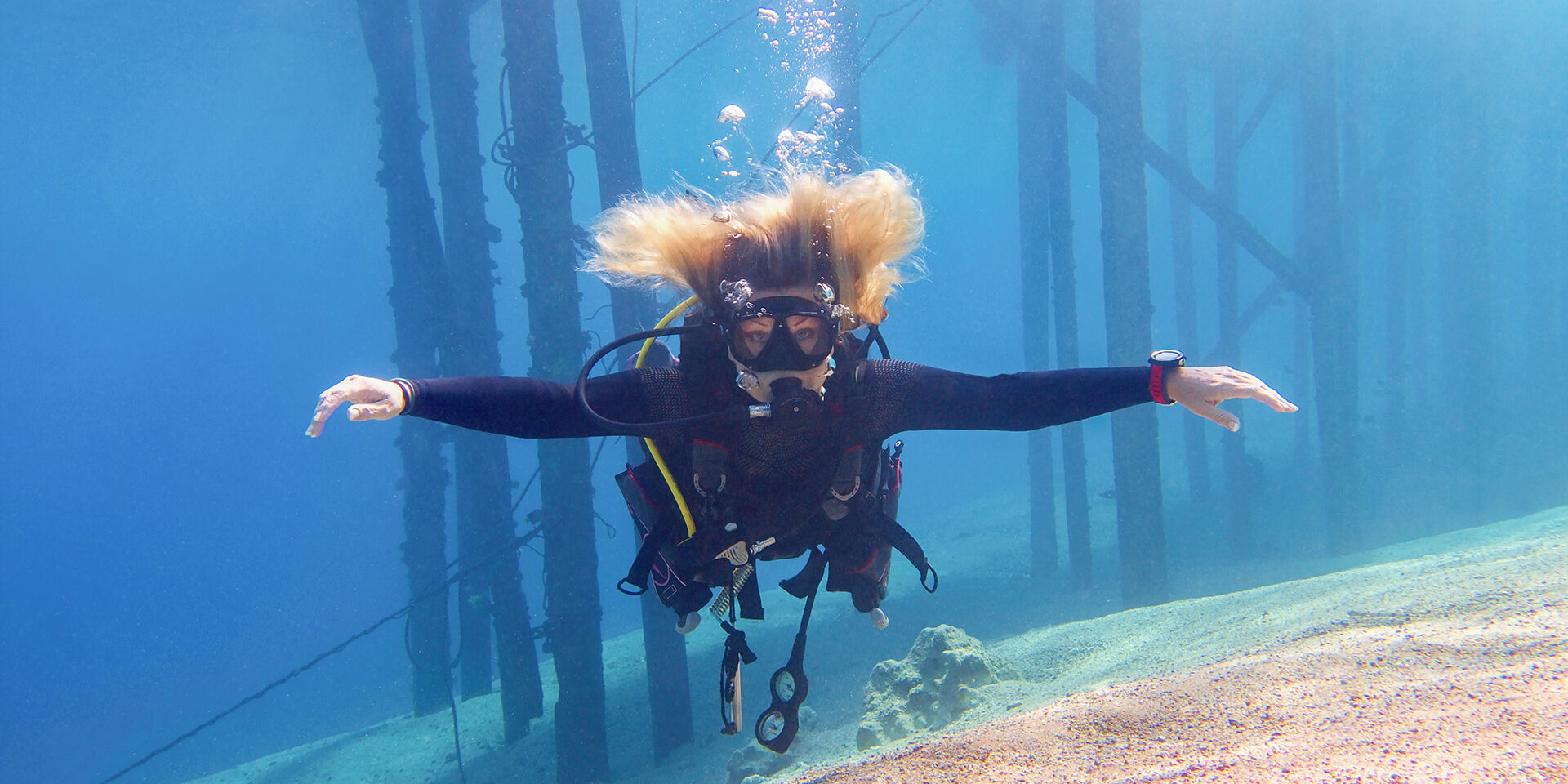 Woman scuba diver freely floating in the blue transparent water enjoing a fun. Woman scuba diver freely floating in the blue transparent water enjoing a fun.