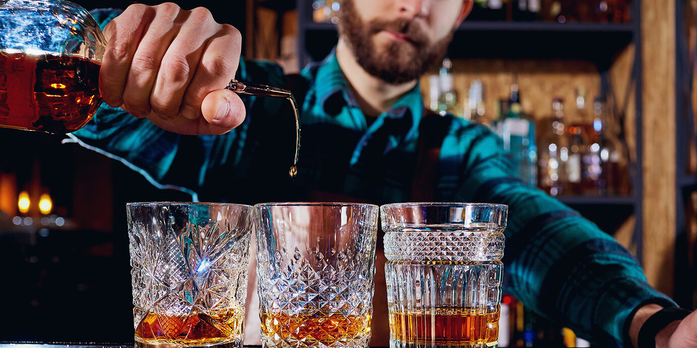 The barman pours alcohol into a glass. Close-up.