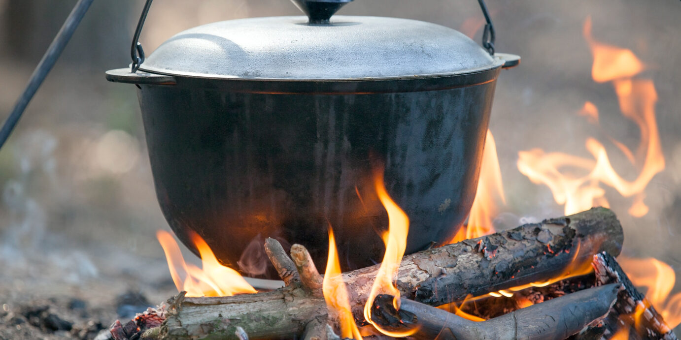 Camping kettle over burning campfire.
