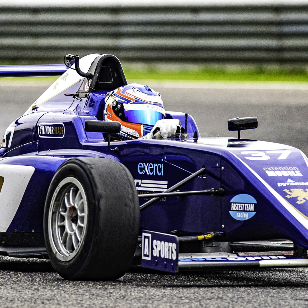 Close-up of a race car driver in a formula car driving fast on the track.