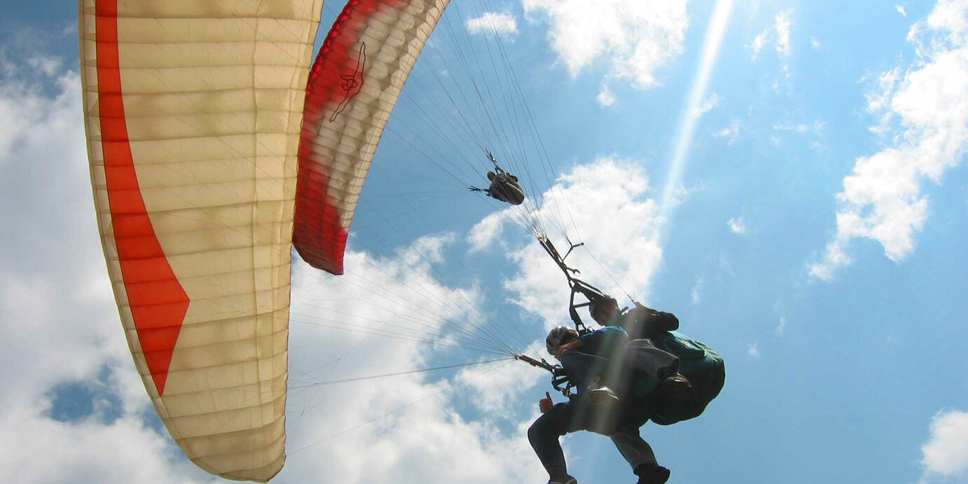 Up shot of person paragliding in the blue sky Paragliding in Medellin, Colombia