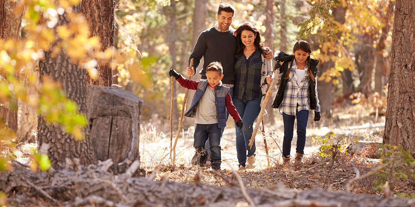 Happy Hispanic family with two children walking in a forest