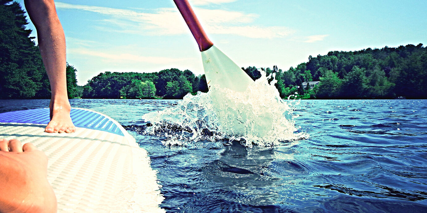 Two figures standing on a paddleboard.