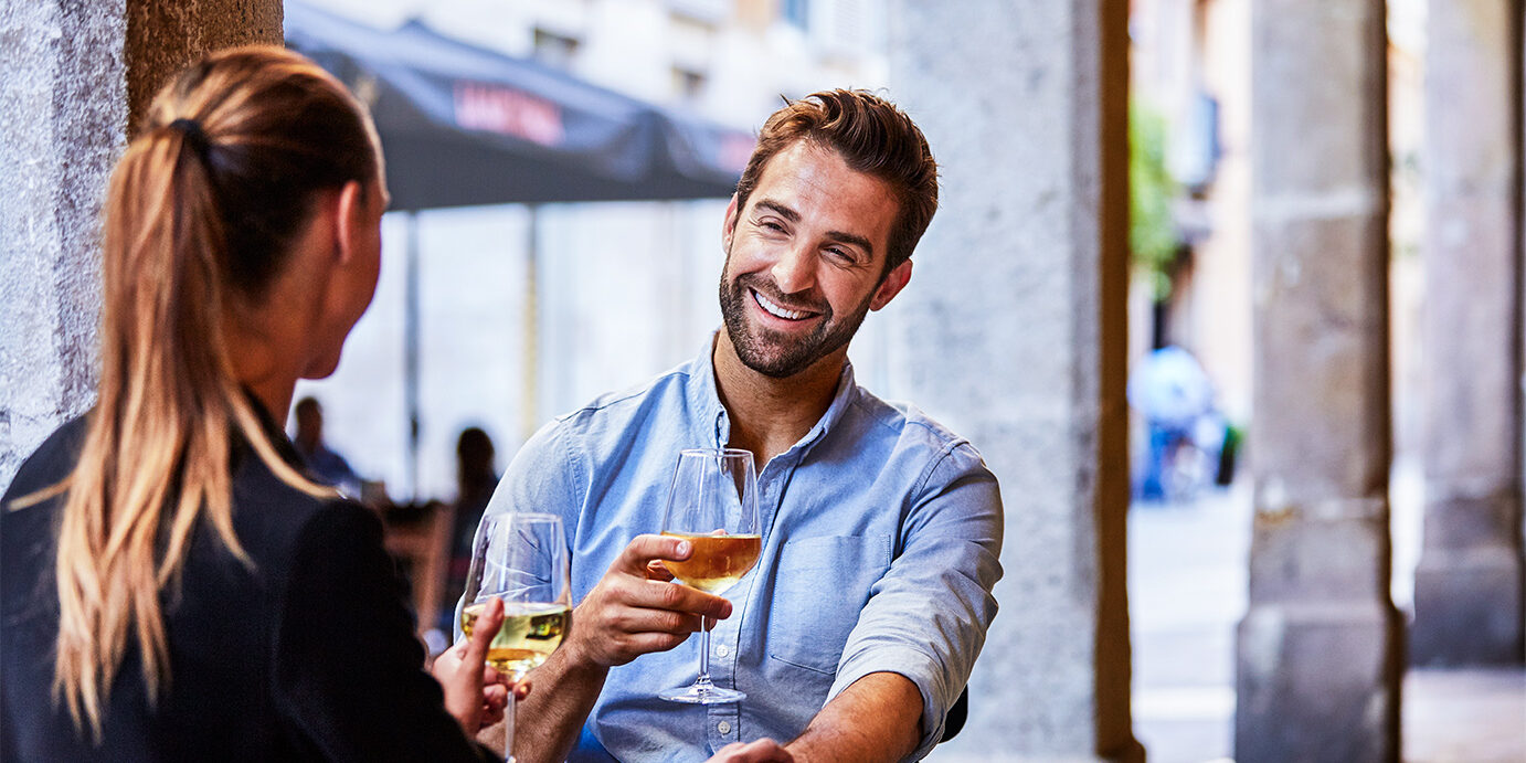 Shot of a young couple sitting at a sidewalk table drinking wine and talking together