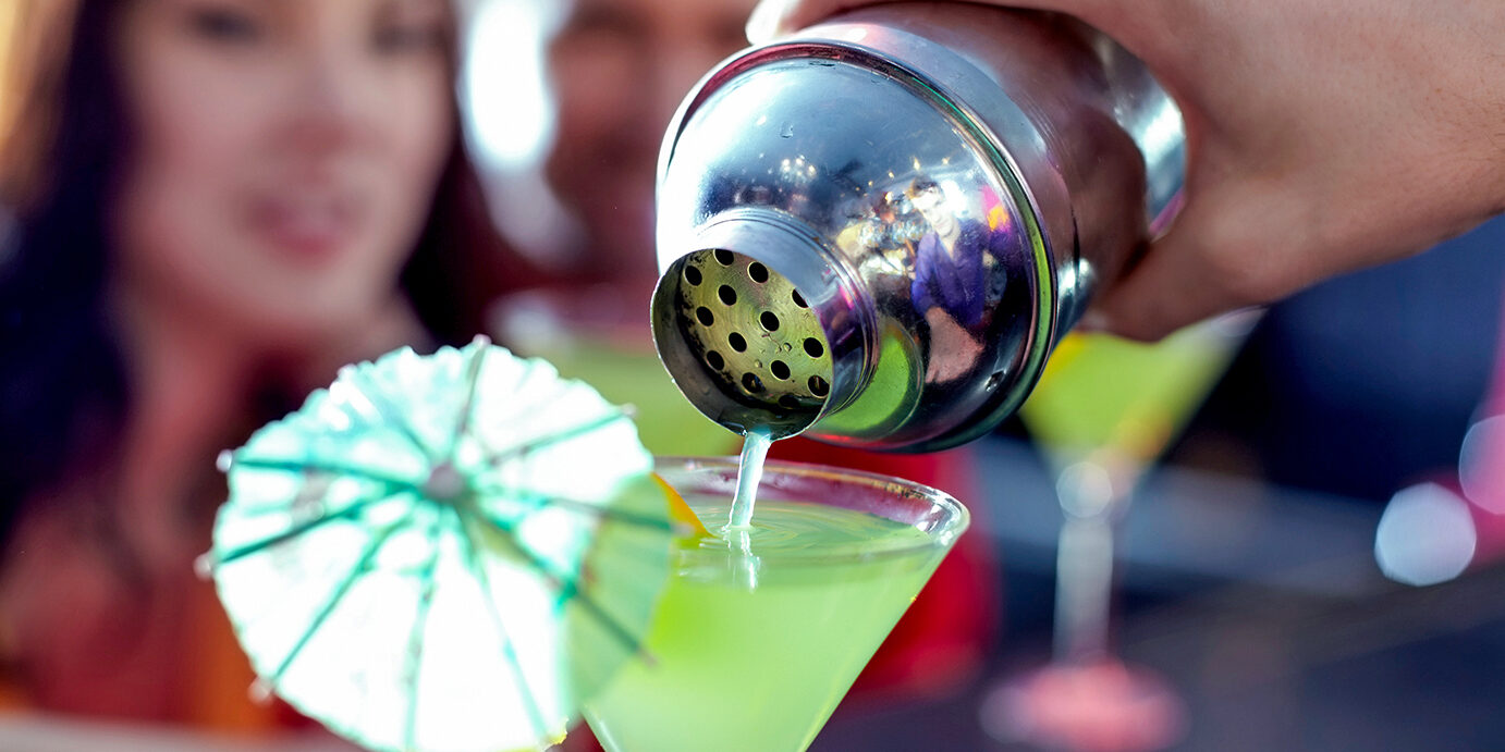 Martini cocktail Close-up of hand of bartender pouring cocktail into martini glass