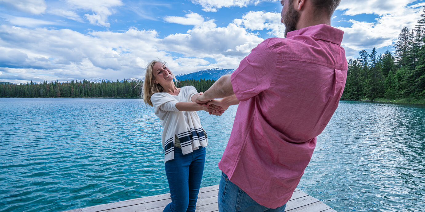 Cheerful young couple on lake pier having fun