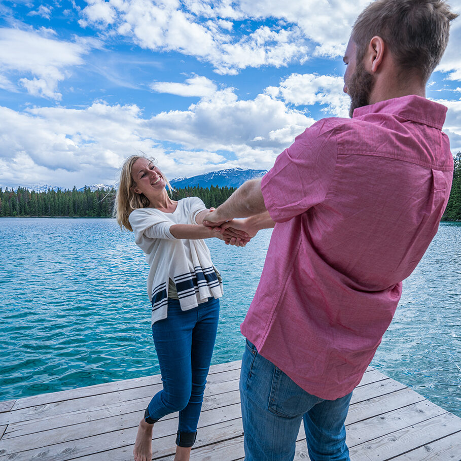 Cheerful young couple on lake pier having fun