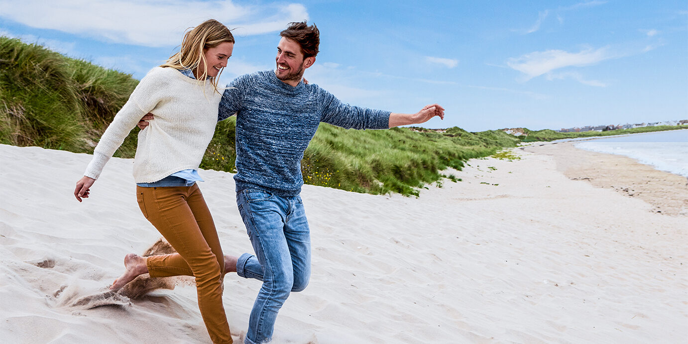 Couple Running Through Sand Dunes Together