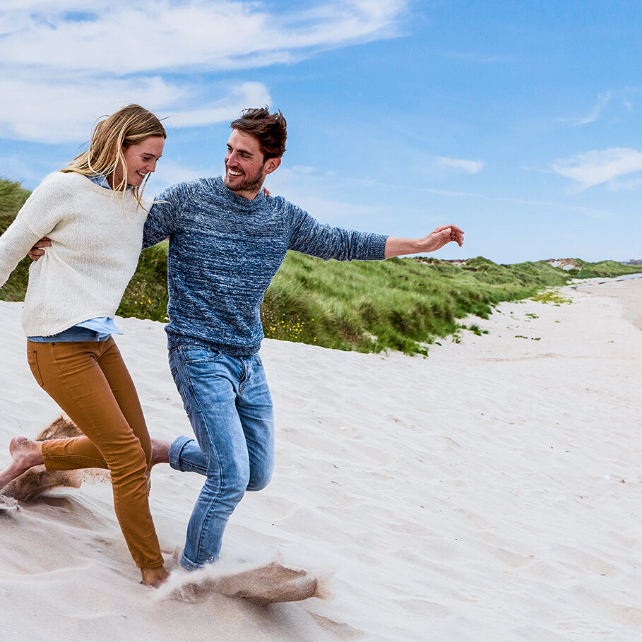 Couple Running Through Sand Dunes Together