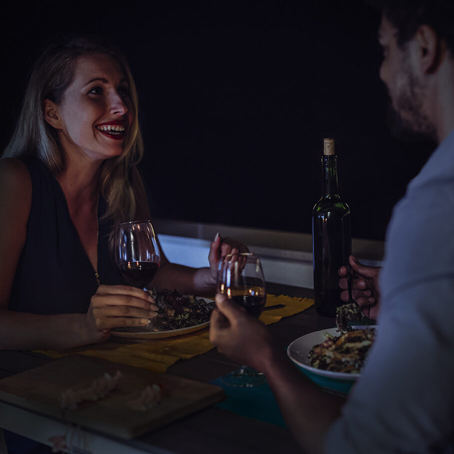 Young beautiful couple in love having romantic dinner at night on rooftop