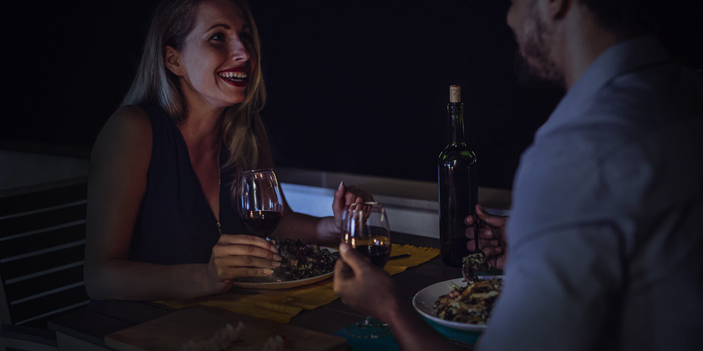 Young beautiful couple having romantic dinner on rooftop Young beautiful couple in love having romantic dinner at night on rooftop