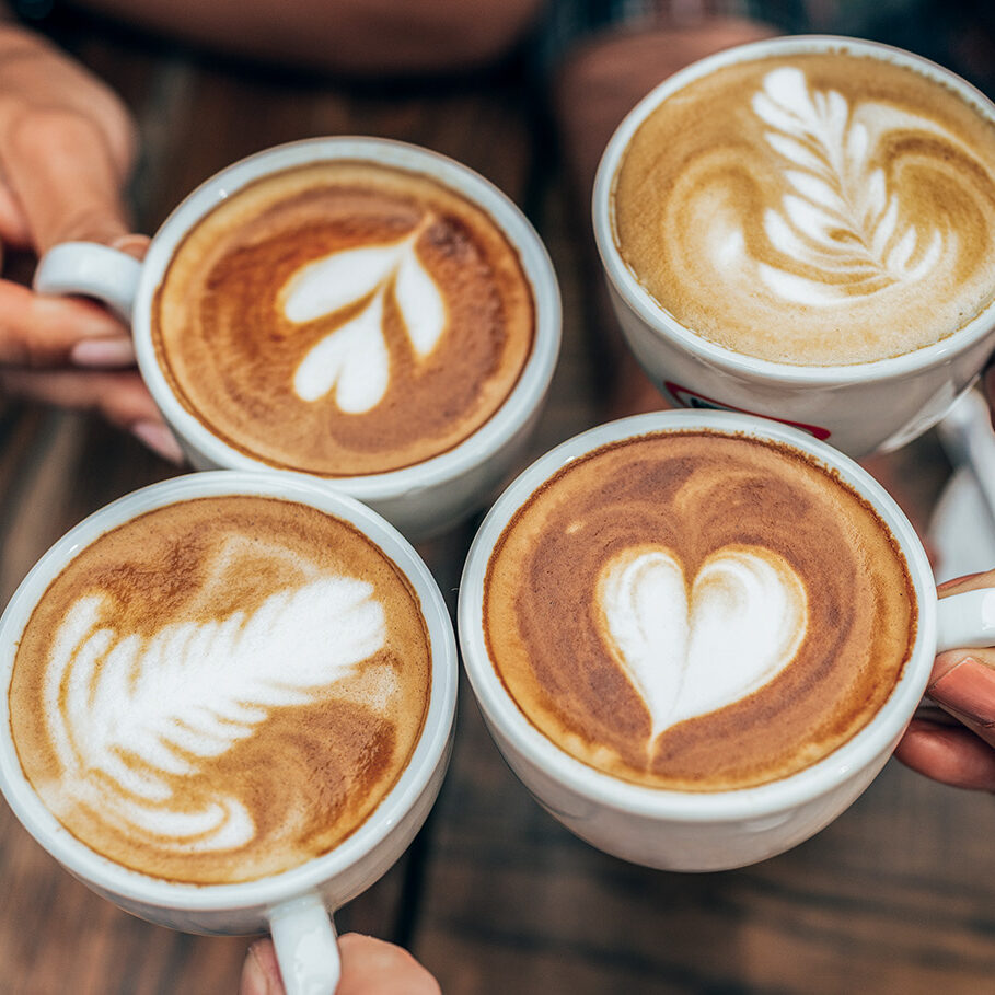 People hands holding cups of cappuccino. Friends drinking coffee together. Hands holding modern looking cups of cappuccino. Tasty and good looking coffee.