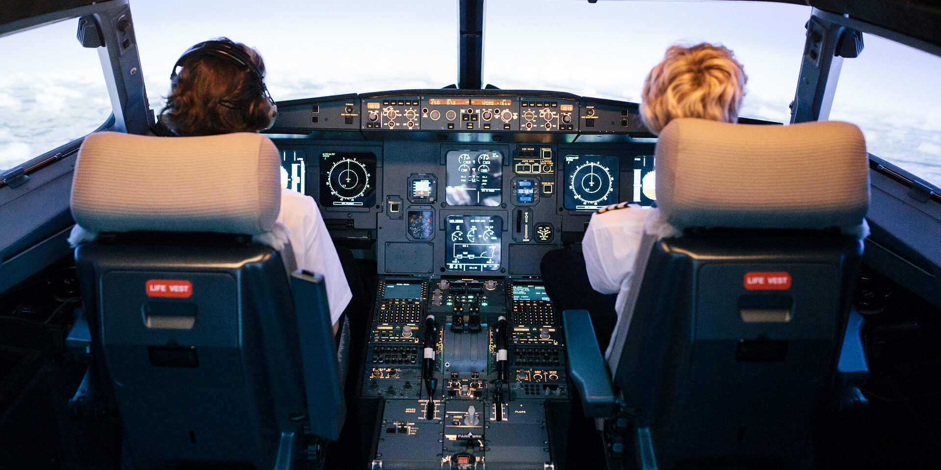 Pilot And Co-Pilot Sitting In Flight Simulator Cockpit A pilot and a trainee co-pilot sitting the cockpit of a flight simulator during a training session.