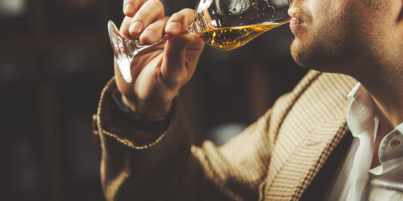 Close-up shot of sommelier tasting whiskey taste on the cellar background. Expert in the field of alcoholic beverages testing drink.
