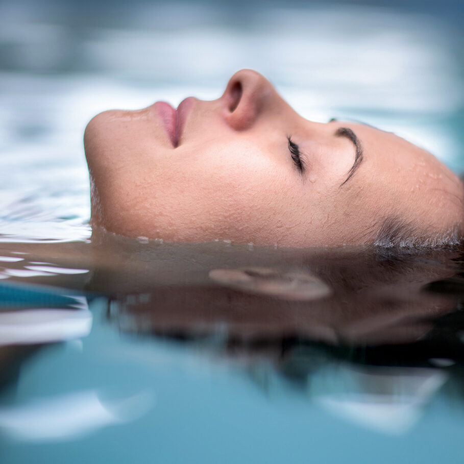 Woman at the spa relaxing at the swimming pool floating with eyes closed