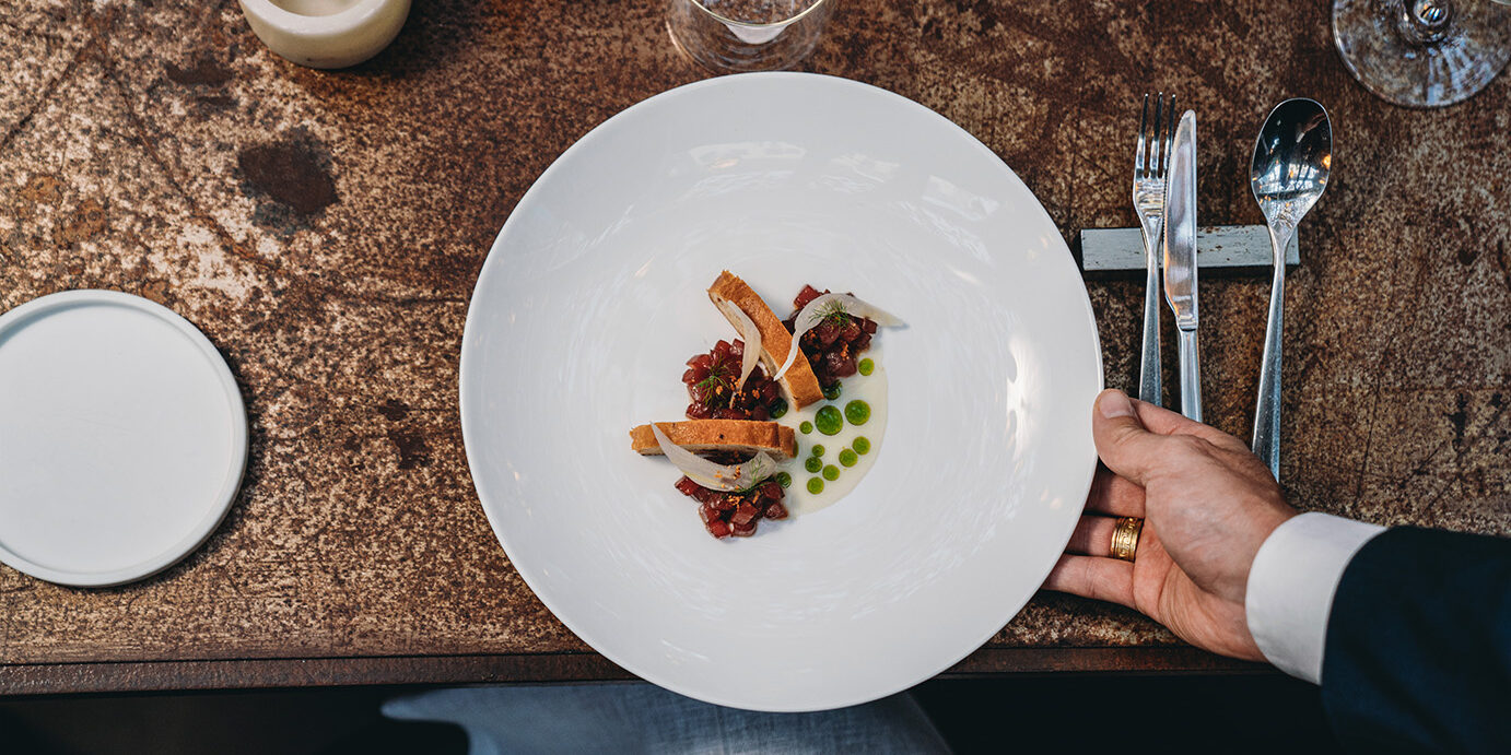 A waiter is serving a plate in an high-end restaurant. Pov view.
