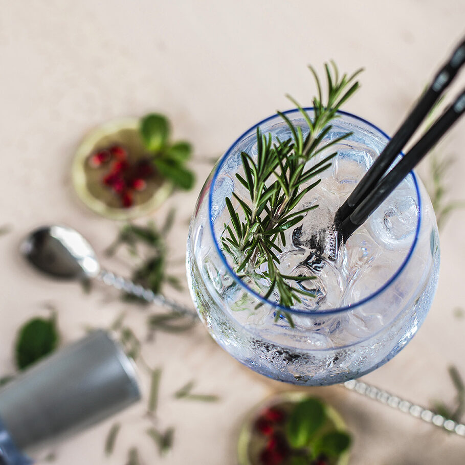 Decorated Gin Soda with a Rosemary Leaf on a wooden desk