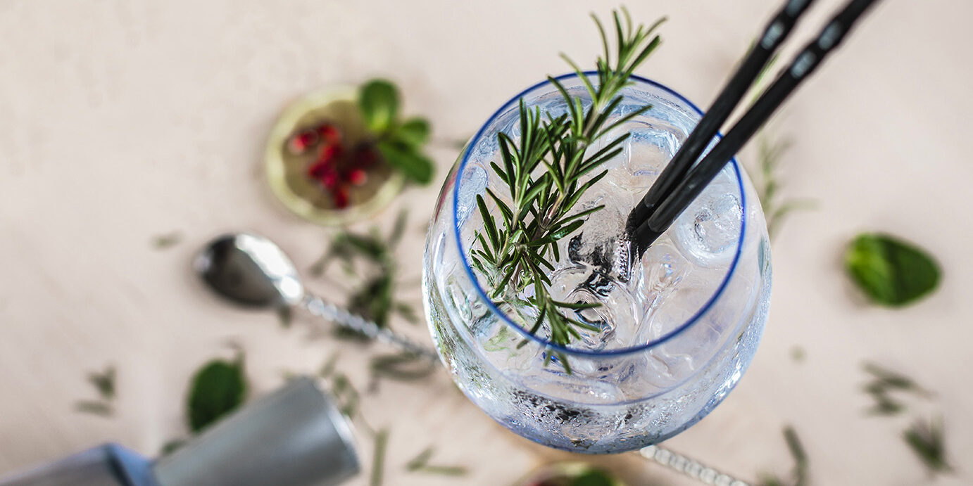 Gin Soda with a Rosemary Decorated Gin Soda with a Rosemary Leaf on a wooden desk