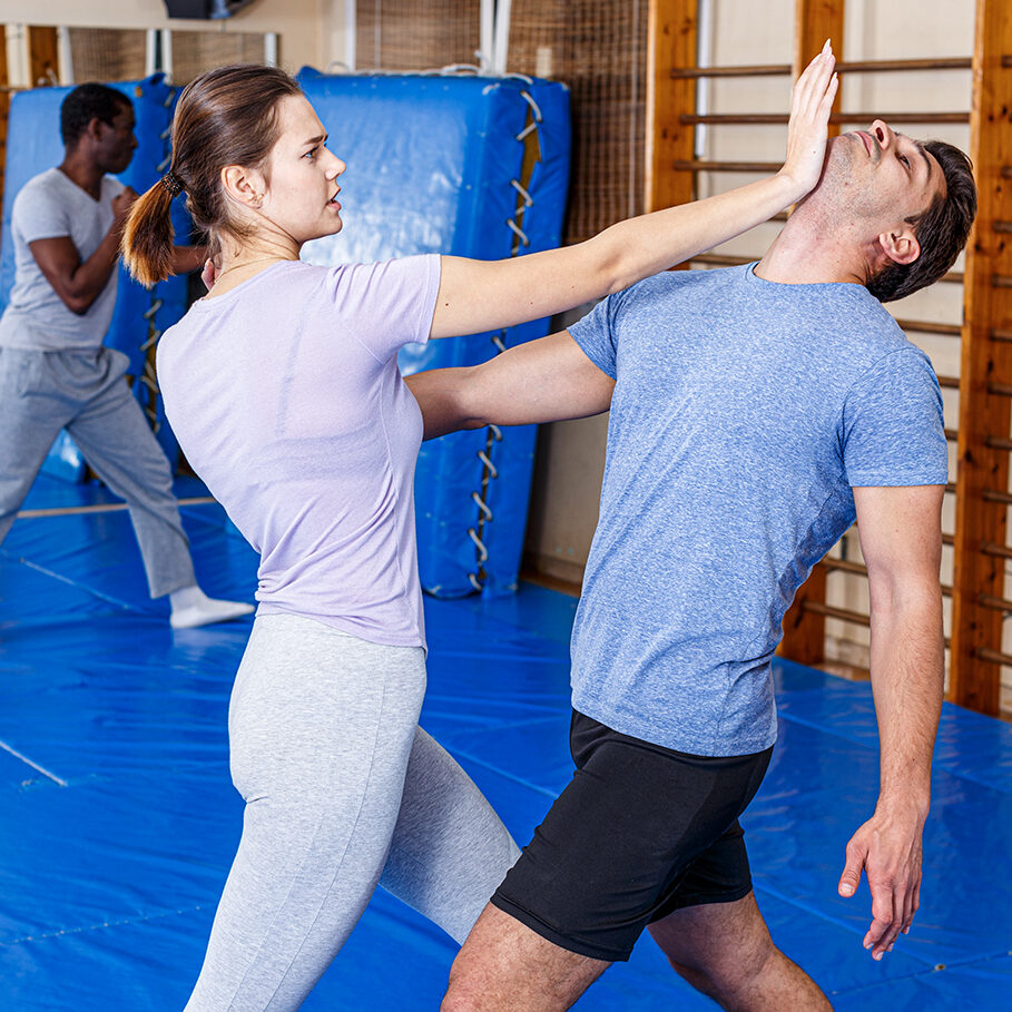 Woman and man practicing self defense techniques in gym