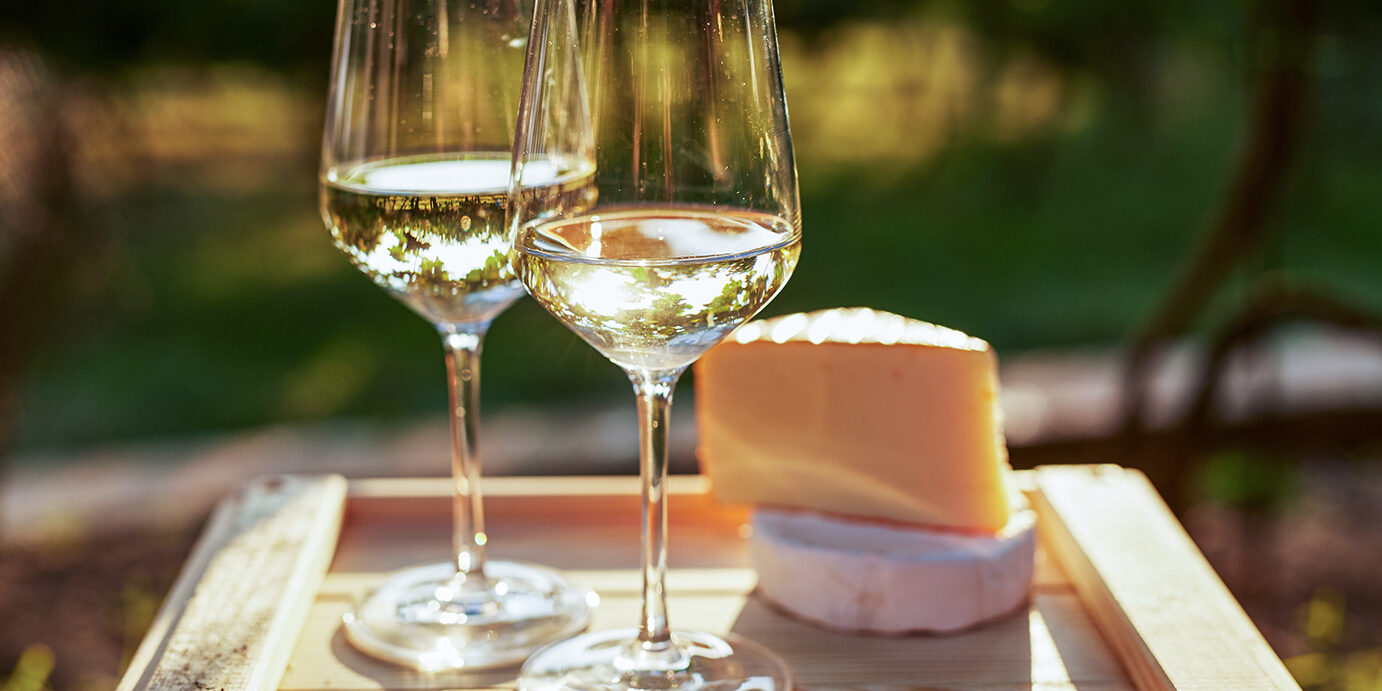 Two glasses of white wine with cheese Two glasses of white wine with cheese on wooden box, toned at sunset