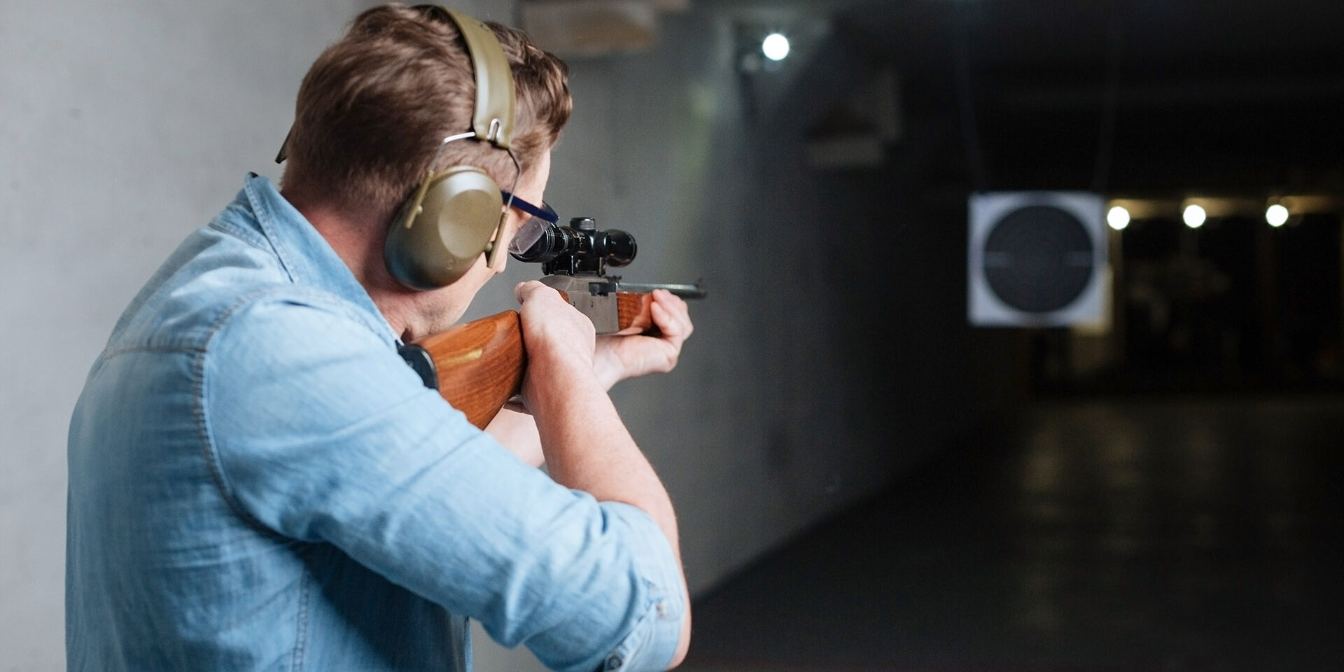 Handsome serious man looking at the target Hitting the bulls eye. Handsome confident serious man holding the rifle and looking into the target while trying to hit the bulls eye