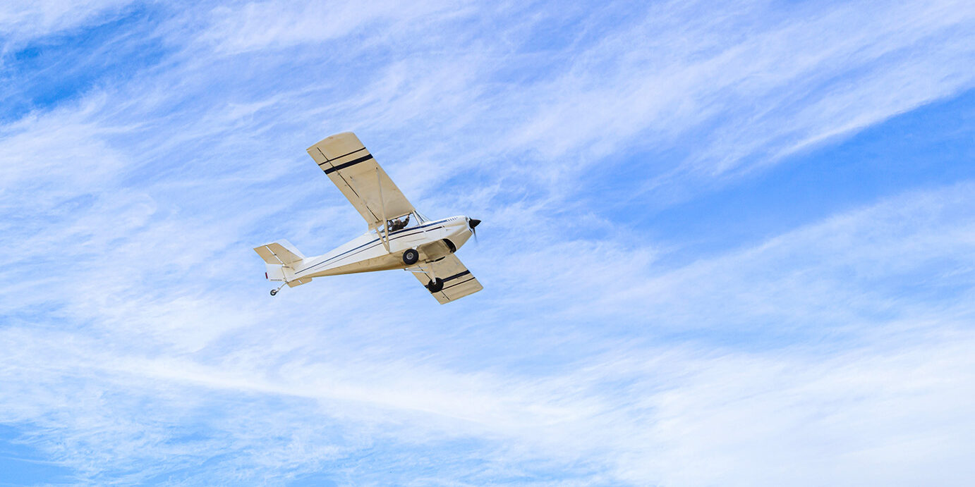 Light aircraft flying over blue sky Single engine ultralight plane flying in the blue sky with white clouds