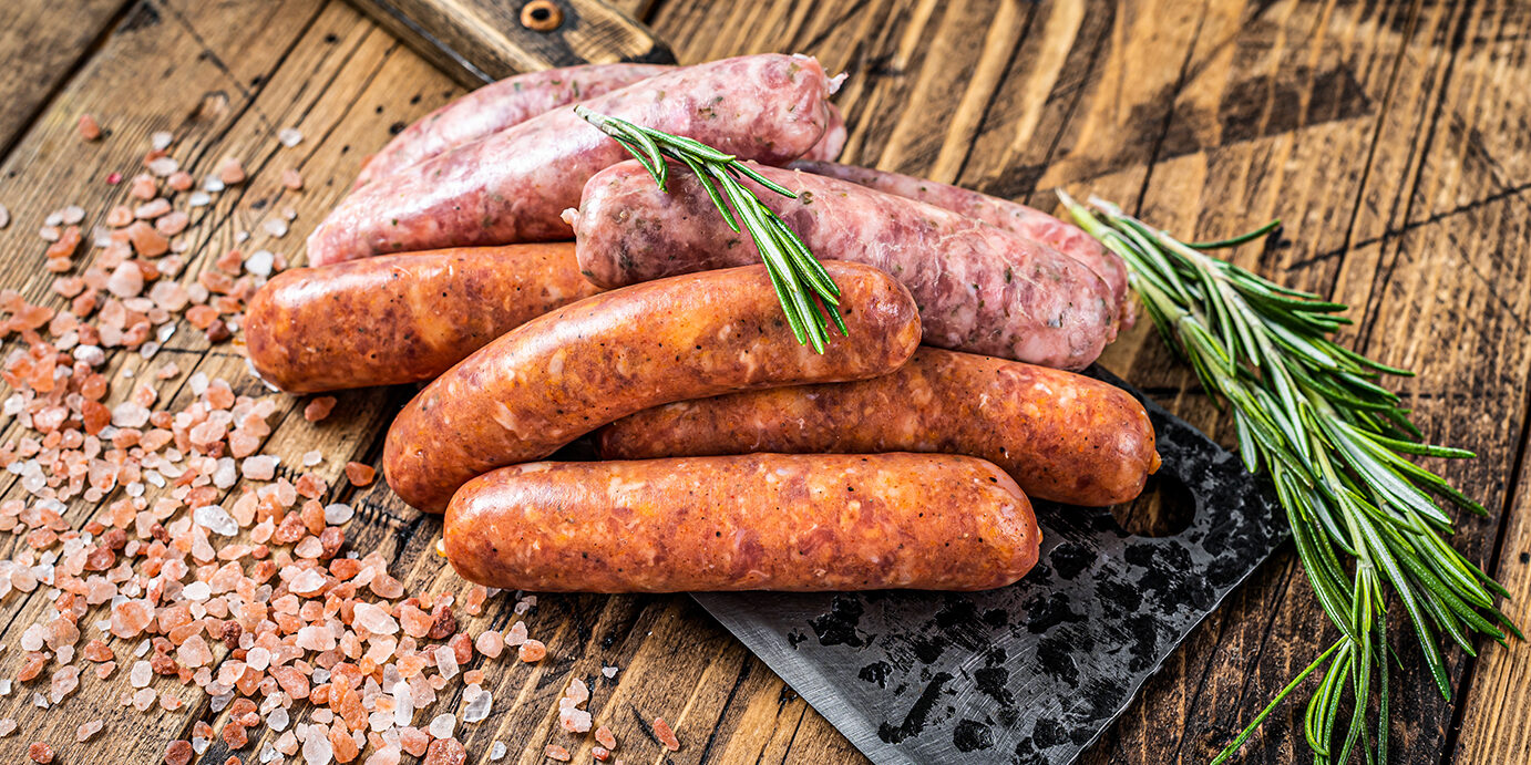 Assorted Raw pork and beef sausages on a butcher meat cleaver. wooden background. Top View Assorted Raw pork and beef sausages on a butcher meat cleaver. wooden background. Top View.